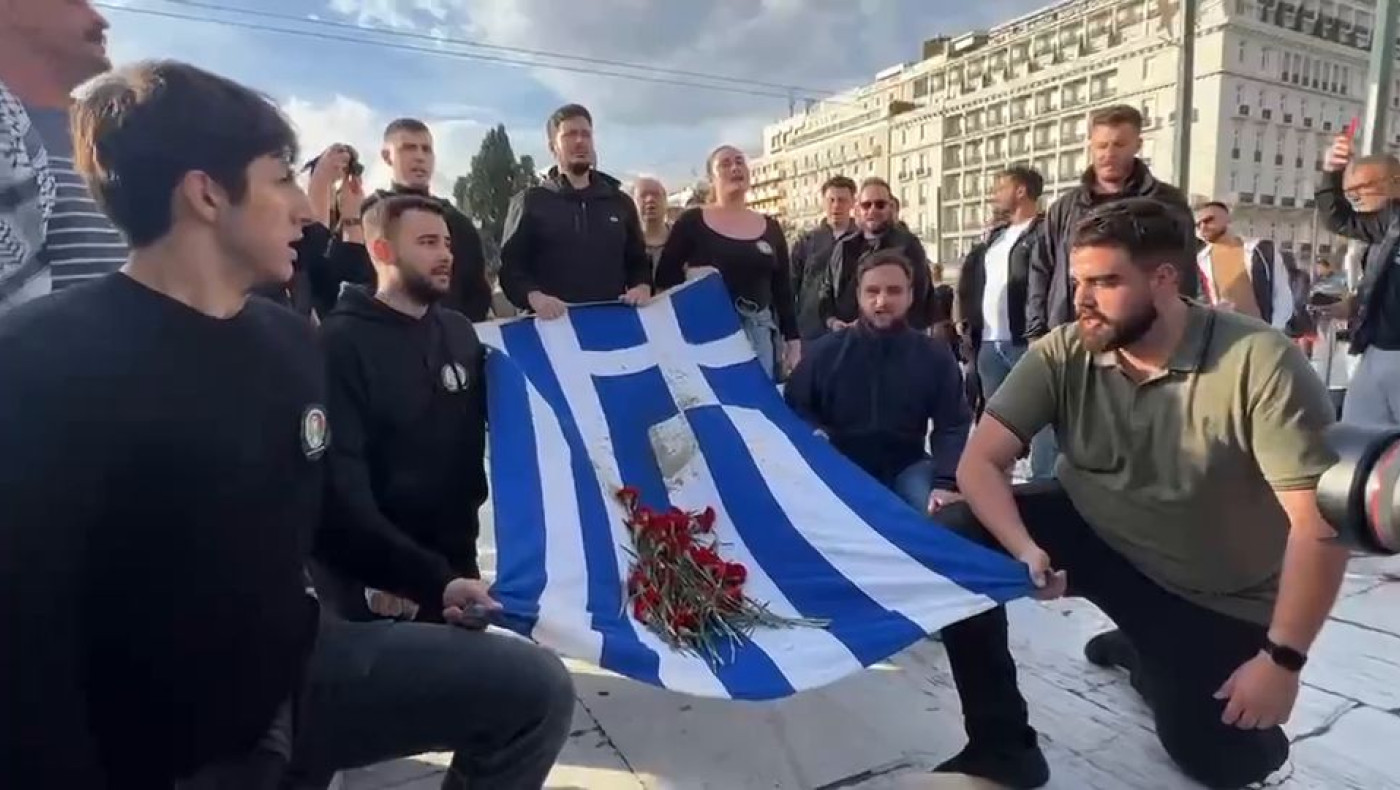 Διαδηλωτές ψέλνουν τον Εθνικό Ύμνο μπροστά από το μνημείο για τα θύματα των Τεμπών στο Σύνταγμα